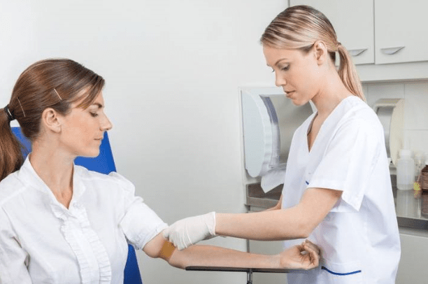 young heath care assistant with blonde hair helping another young woman with a blood test